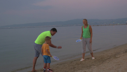 男孩和父母在海滩上玩打球的游戏视频