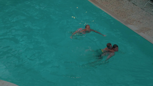 年轻的父母和小儿子在游泳池里游泳视频