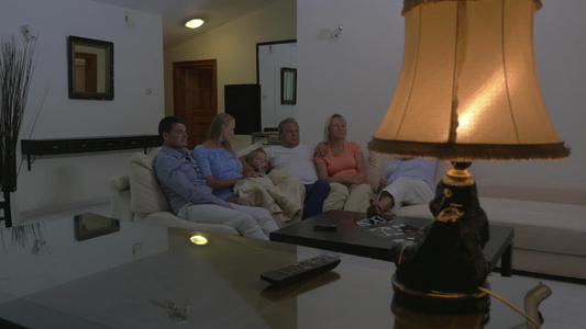 一家人晚上坐在沙发上看电视视频