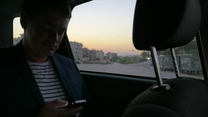 年轻男人坐在车里看智能手机里的信息16秒视频