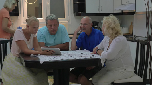 家庭成员几个老年人坐在餐桌旁用平板电脑讨论一些事情视频