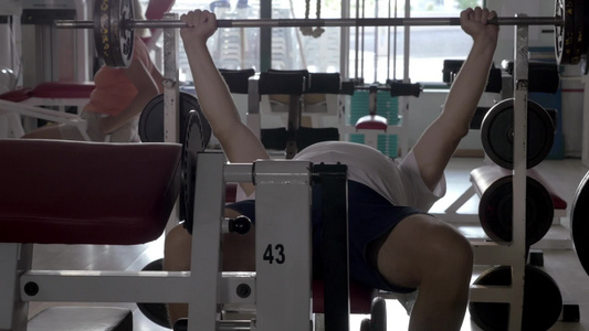 年长的男人锻炼杠铃女人在健身机上锻炼[几岁]视频