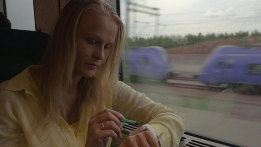 年轻的女人坐在火车的窗边使用智能手表视频