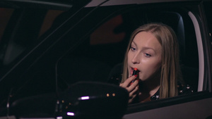 晚上站在城市街道的路边看着汽车的侧面后视镜漂亮的女司机正在涂红色口红特写18秒视频
