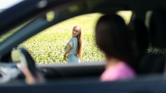 女司机打开车窗叫上正在花田间欣赏自然景色的长发女孩一起出发视频