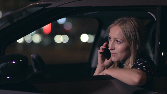 一个漂亮的金发女人坐在驾驶座上打电话视频