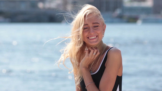 在海滩上摆姿势的年轻漂亮金发女人的特写视频