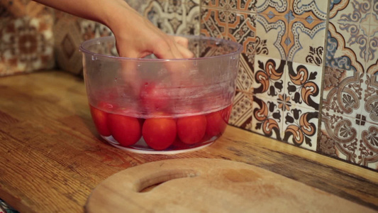 女性从塑料碗中取出烫好的西红柿剥皮视频