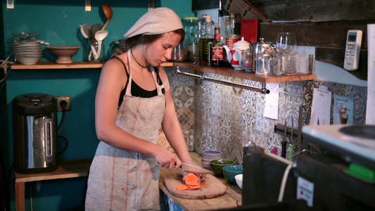 年轻的女人在厨房的木制砧板上切萝卜视频