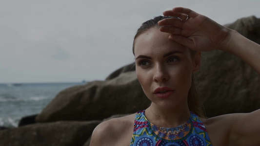 特写站在海边岩石间穿着比基尼的年轻女性视频