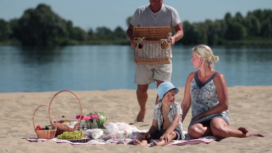 年轻夫妇和小男孩一起去海滩野餐[野餐盒]视频