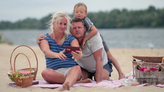 欢快的一家人坐在海滩上自拍视频