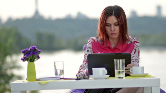 女人坐在户外咖啡馆里进行网上购物视频