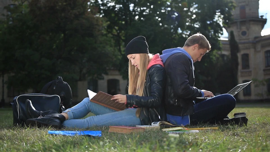 情侣背靠背坐在公园里学习视频
