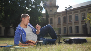 英俊的学生坐在校园草坪上学习15秒视频