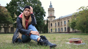一个女学生有些不快乐独自坐在大学外面的草地上发呆14秒视频