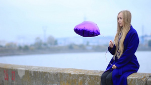 美丽悲伤的金发女人拿着紫色的气球坐在栏杆上13秒视频