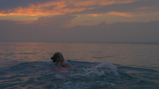 日落时分一个年轻女人在平静的大海里游泳视频