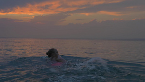 日落时分一个年轻女人在平静的大海里游泳19秒视频