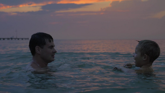 日落时父亲和儿子在海里游泳视频