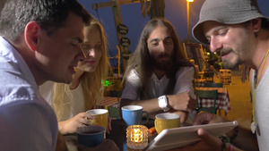 晚上在希腊的佩雷亚市咖啡馆坐着几个年轻男女在讨论平板电脑上的信息17秒视频