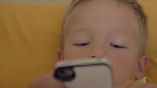 特写镜头的小男孩在智能手机上玩游戏视频