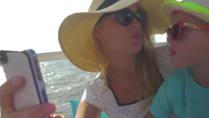 夏日海边戴着帽子和太阳镜的母亲和她的孩子正在游船上自拍18秒视频