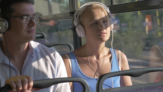 两个年轻人坐在公交上带着耳机听歌视频