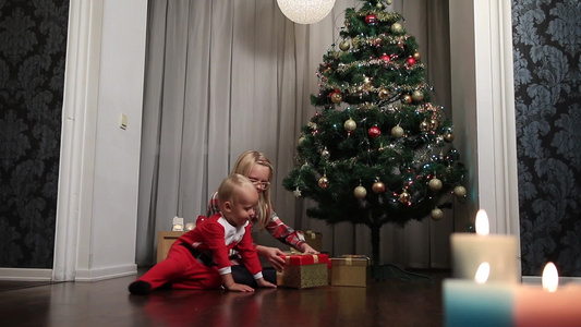 女孩和小男孩穿着圣诞服装打开圣诞礼物视频