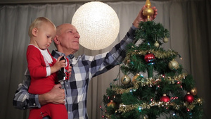 祖父抱着孙子在家里装饰圣诞树6秒视频