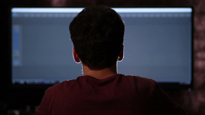 男子坐在电脑前剪辑视频的背影16秒视频