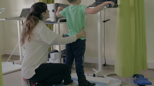 小男孩在医疗诊所在机器人系统分析和训练平衡视频