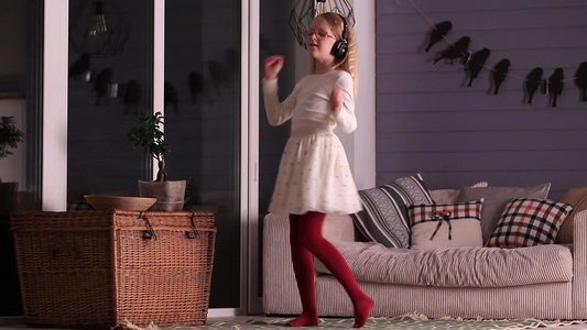 小女孩在客厅戴着耳机听音乐跳舞视频