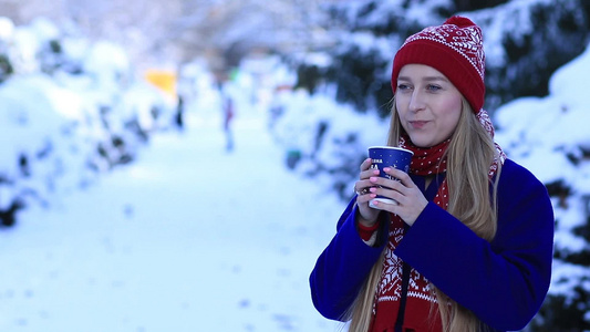 冬季女孩站在户外喝着热饮料[男孩儿]视频