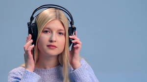 漂亮的女孩在白色背景上听耳机里的音乐面部表情特写25秒视频