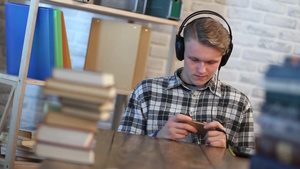 图书馆里开朗的学生在玩手机听音乐7秒视频