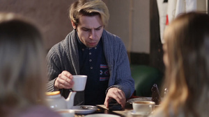 自信的年轻潮人坐在咖啡馆和朋友一起喝咖啡同时浏览手机信息14秒视频