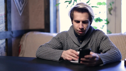 年轻男士坐在咖啡店里玩手机视频