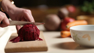 女人用菜刀在木制砧板上把甜菜切成薄片放进碗里26秒视频
