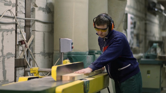 工人戴安全眼镜和耳罩在做电锯整平板视频