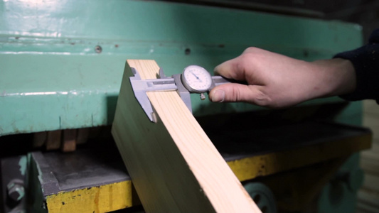  在车间工作的木工用卡尺测量木板的过程特写视频