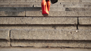 穿着橙色的高跟鞋行走在城市的石阶上16秒视频
