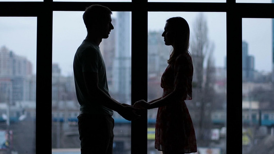 一对相爱的夫妇在城市景观窗前牵手的剪影视频