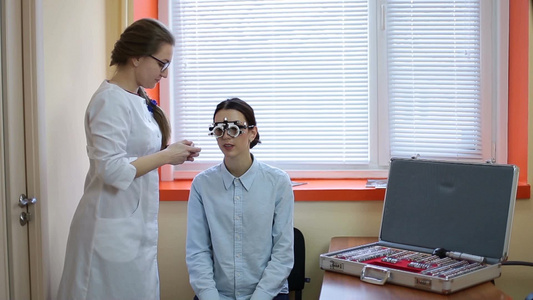 验光师在眼科诊所用试验框架检查女性患者视频