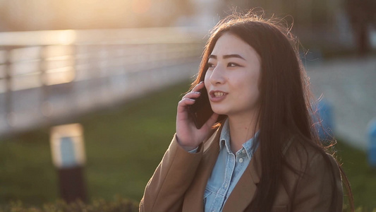  美丽的年轻女性在公园里用手机和朋友交流视频