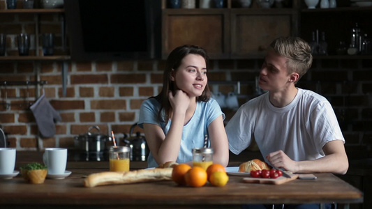 年轻情侣夫妇坐在厨房餐桌交谈视频