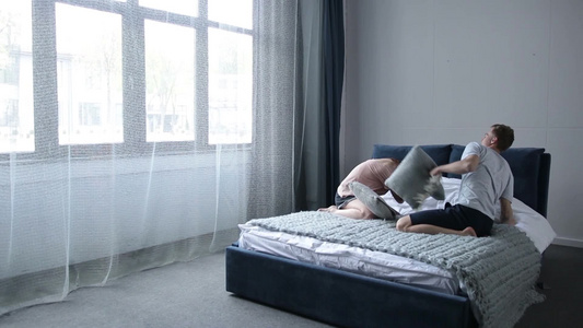 年轻的情侣在床上玩枕头大战视频