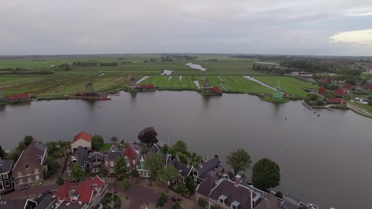 空中拍摄荷兰水边风车和绿色田野视频