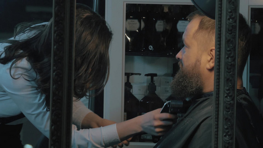 女理发师用电动剃须刀修剪胡须[剪修]视频