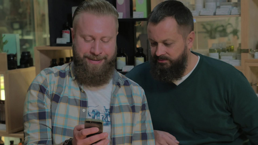 两个成熟的有胡须的男人在手机上浏览网页视频